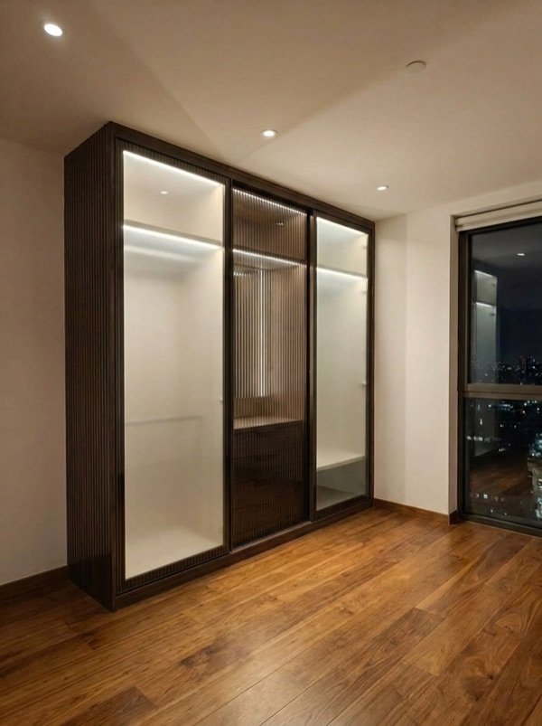 Sliding wardrobe with glass doors in a compact Hyderabad bedroom